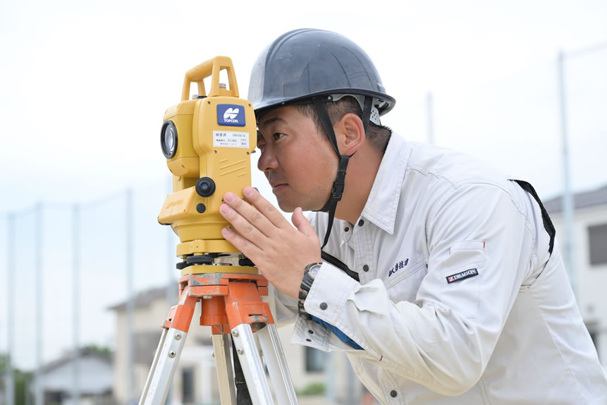 ヘルメットを被った男性が、黄色の工具を覗いて仕事している