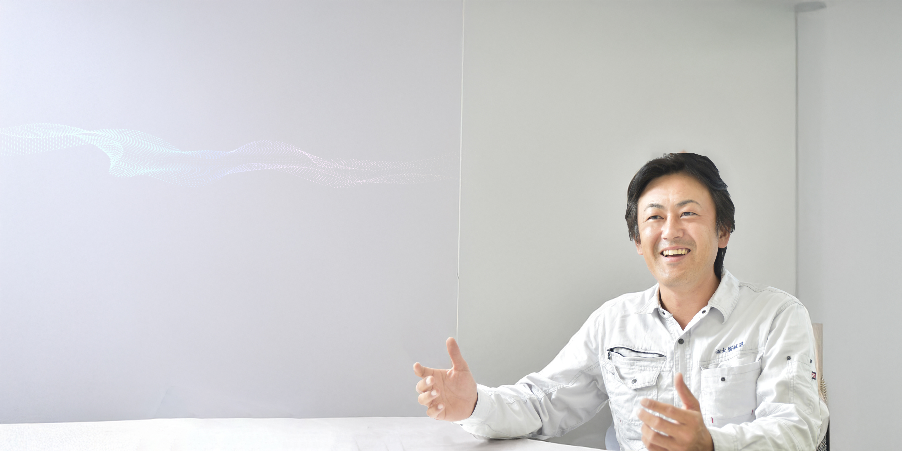 作業着を着た男性が手を広げて語りかける様子