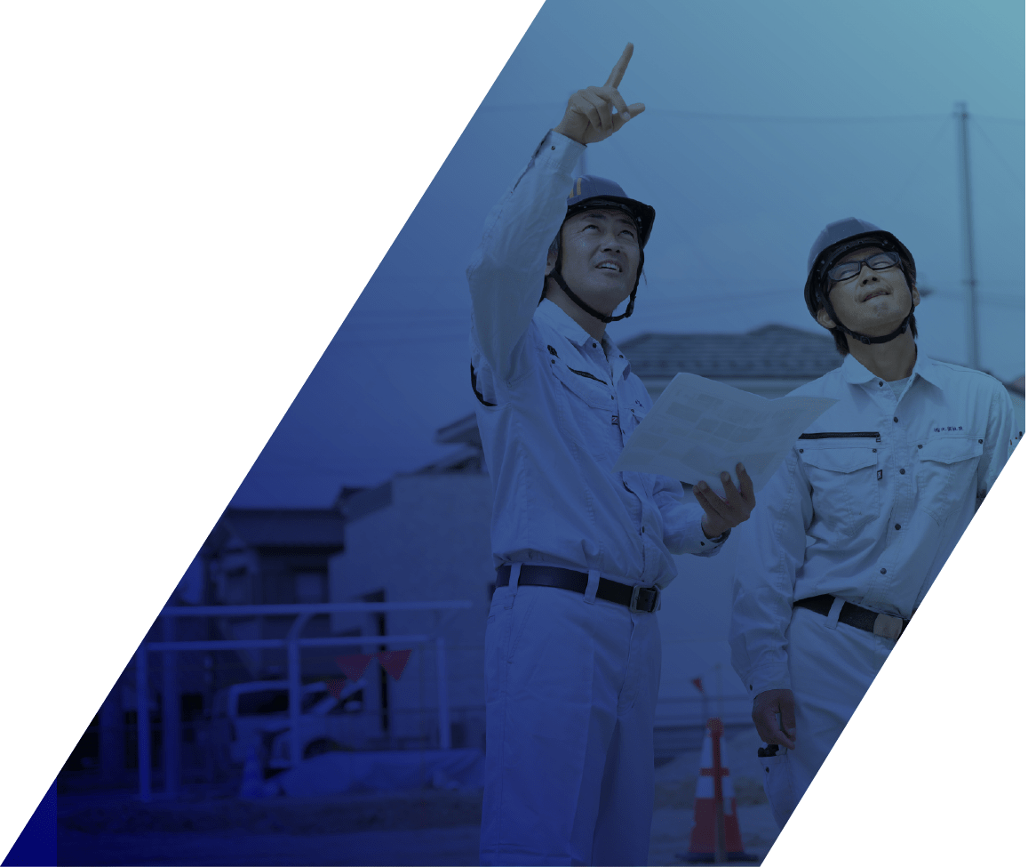 ヘルメットと作業着を着用した男性2人が指を指して、上を見上げている